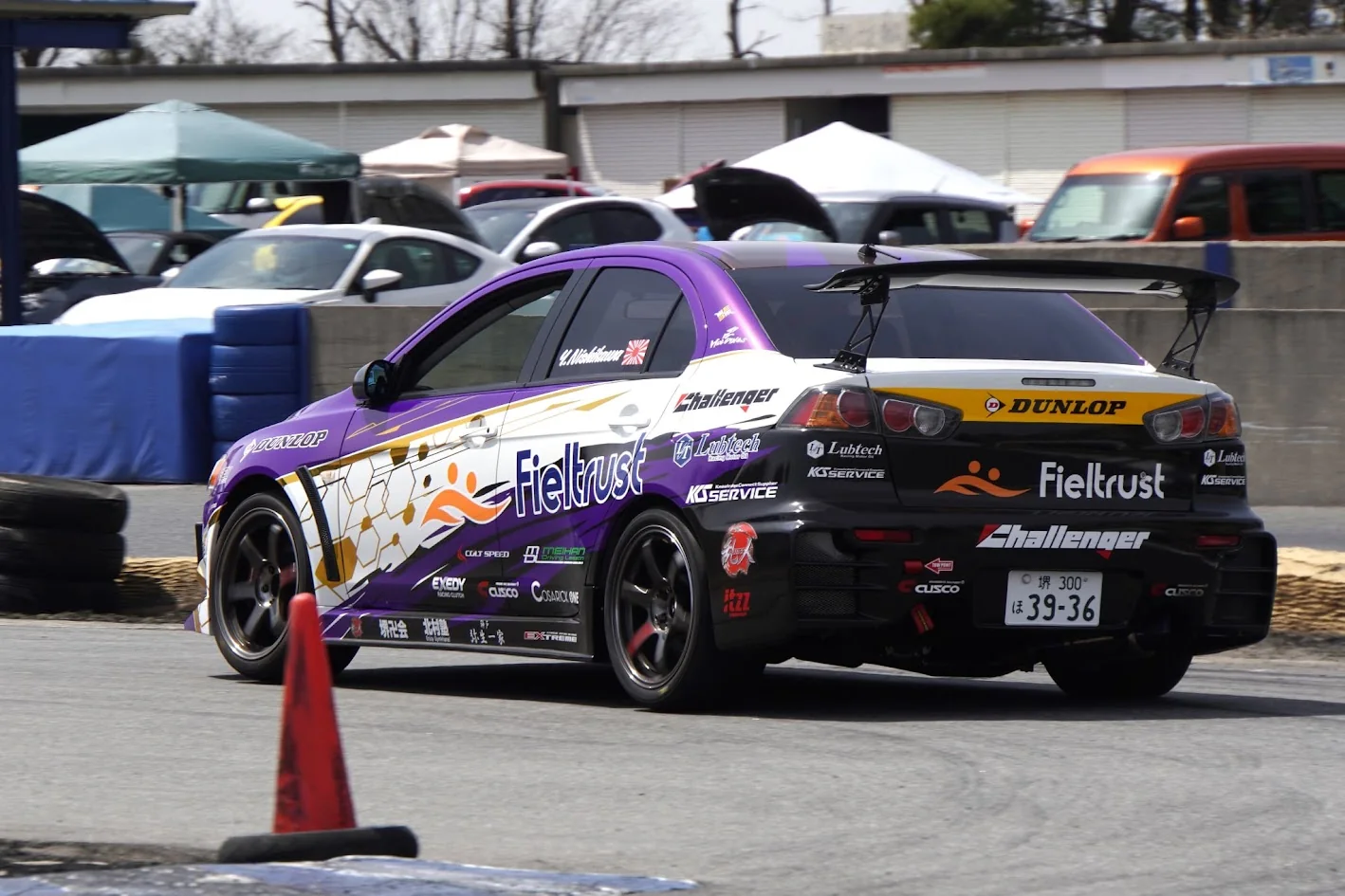 パドック付近を走行する紫と黄色の競技車両